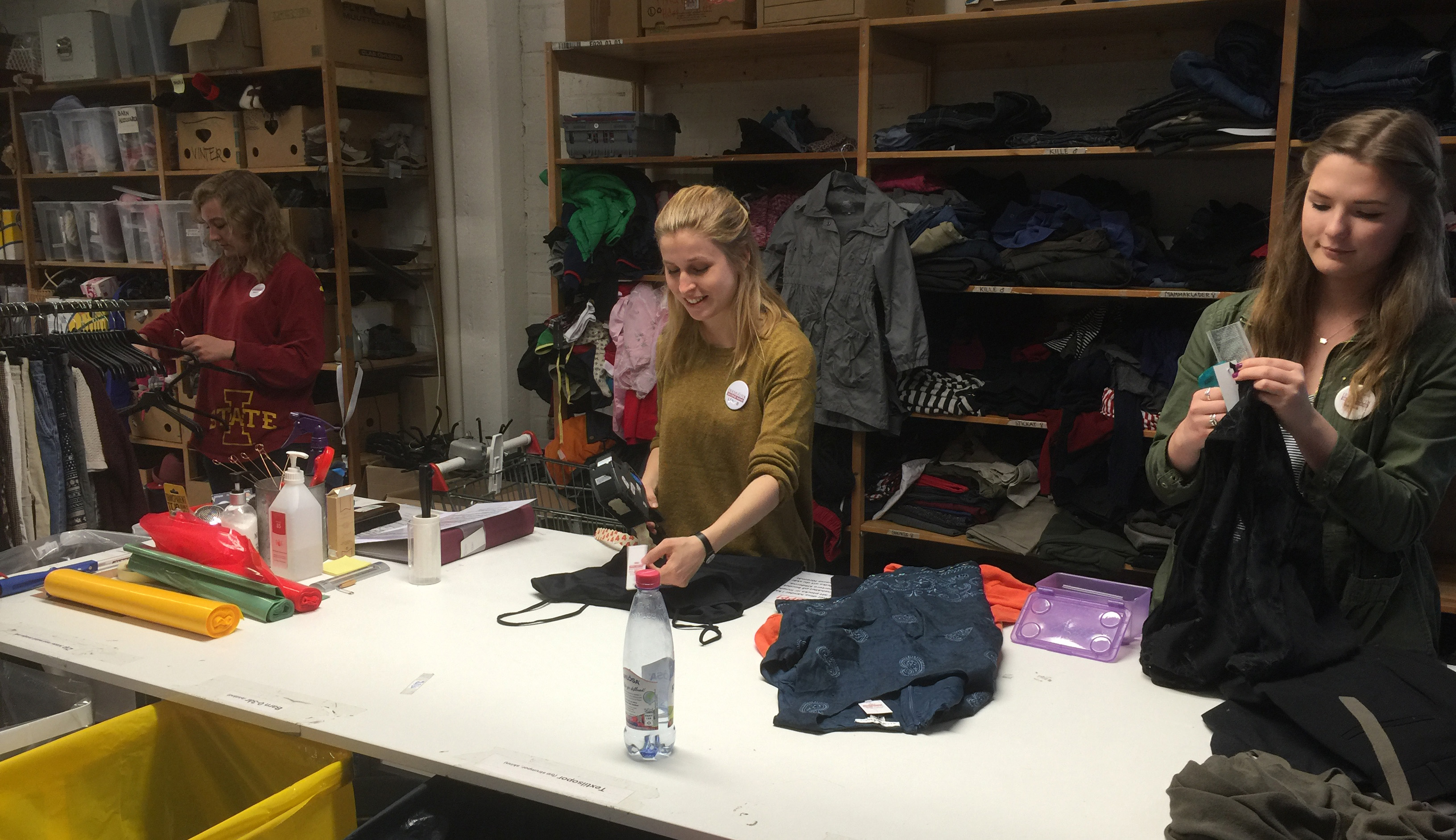 Student volunteers Emma Grace Reese (left) and Emma Bruen (right) work with a staff member at Erikshjälpen Second Hand.