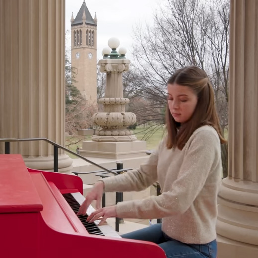 Lydia lee playing the piano with the campanile in the background