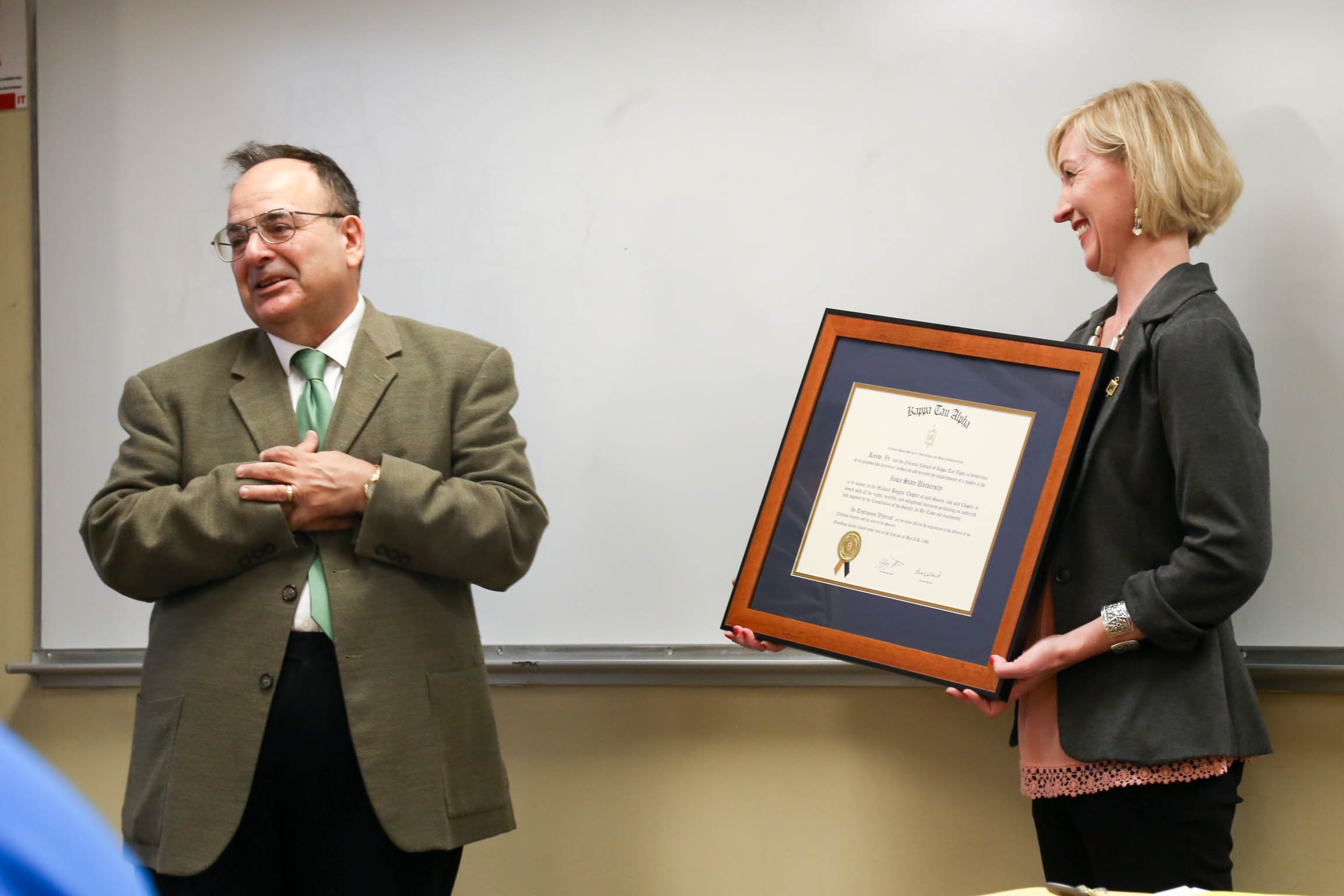 Tracy Lucht, assistant professor and Kappa Tau Alpha adviser, presents Michael Bugeja, outgoing director, a certificate stating the ISU Kappa Tau Alpha chapter has been named after him. 