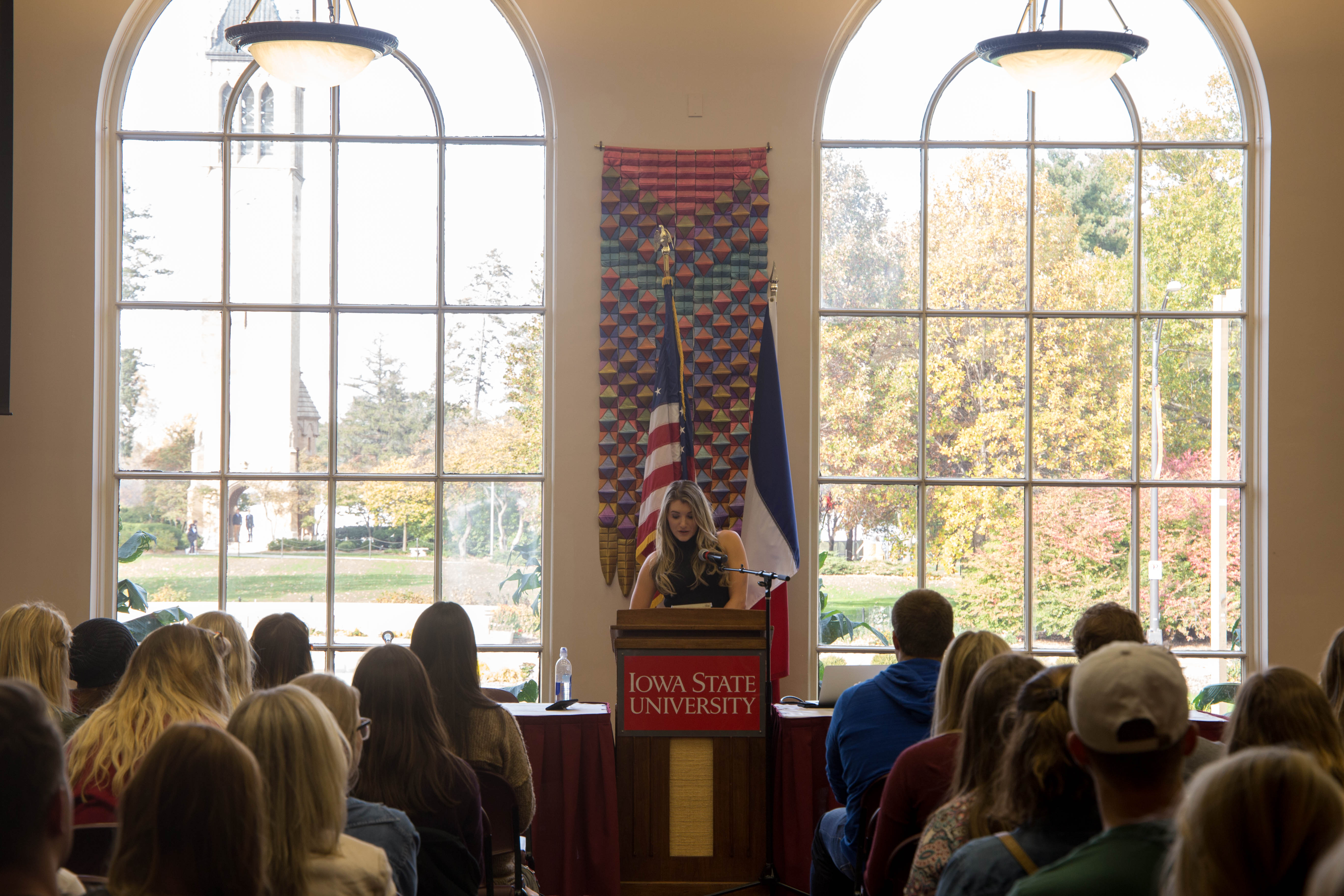 A photo taken straight-on of Kelly Howard as she stands at the podium in the Memorial Union Campanile Room.
