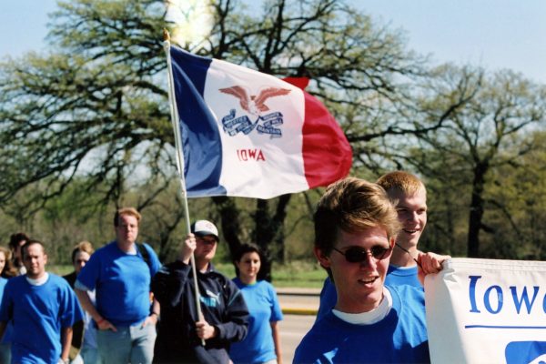 students marching with flag of Iowa