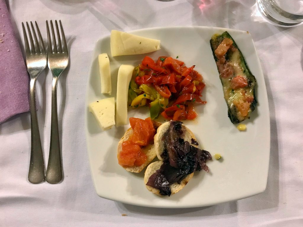 Antipasti on a white plate next to two forks.