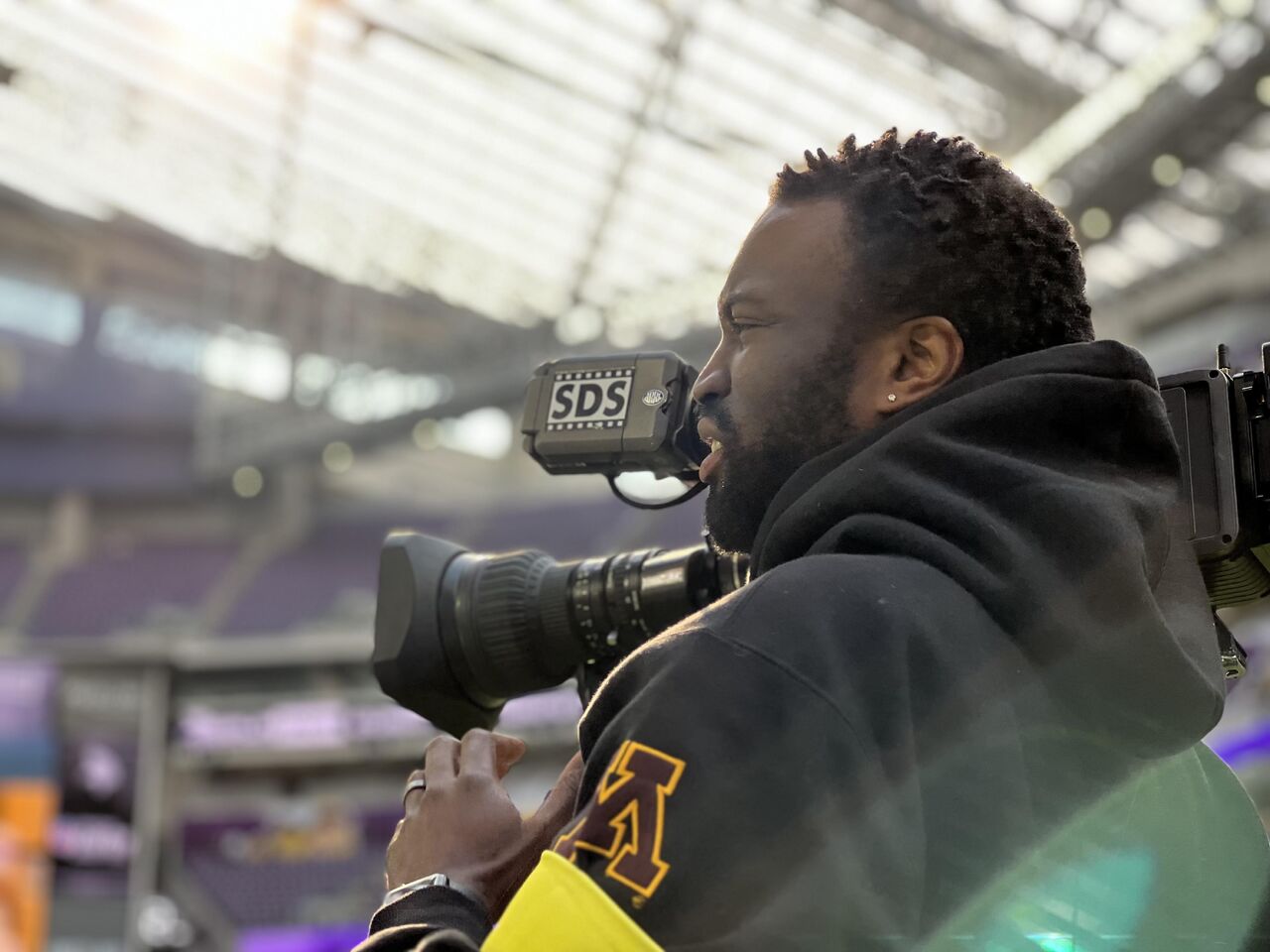 Jairus Davis holds video camera on sidelines.