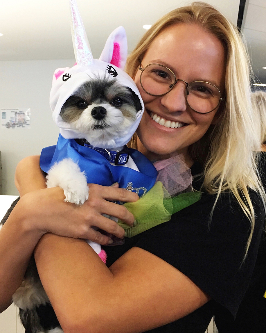 Tiffany smiles for the camera. She is wearing glasses and has blonde hair.