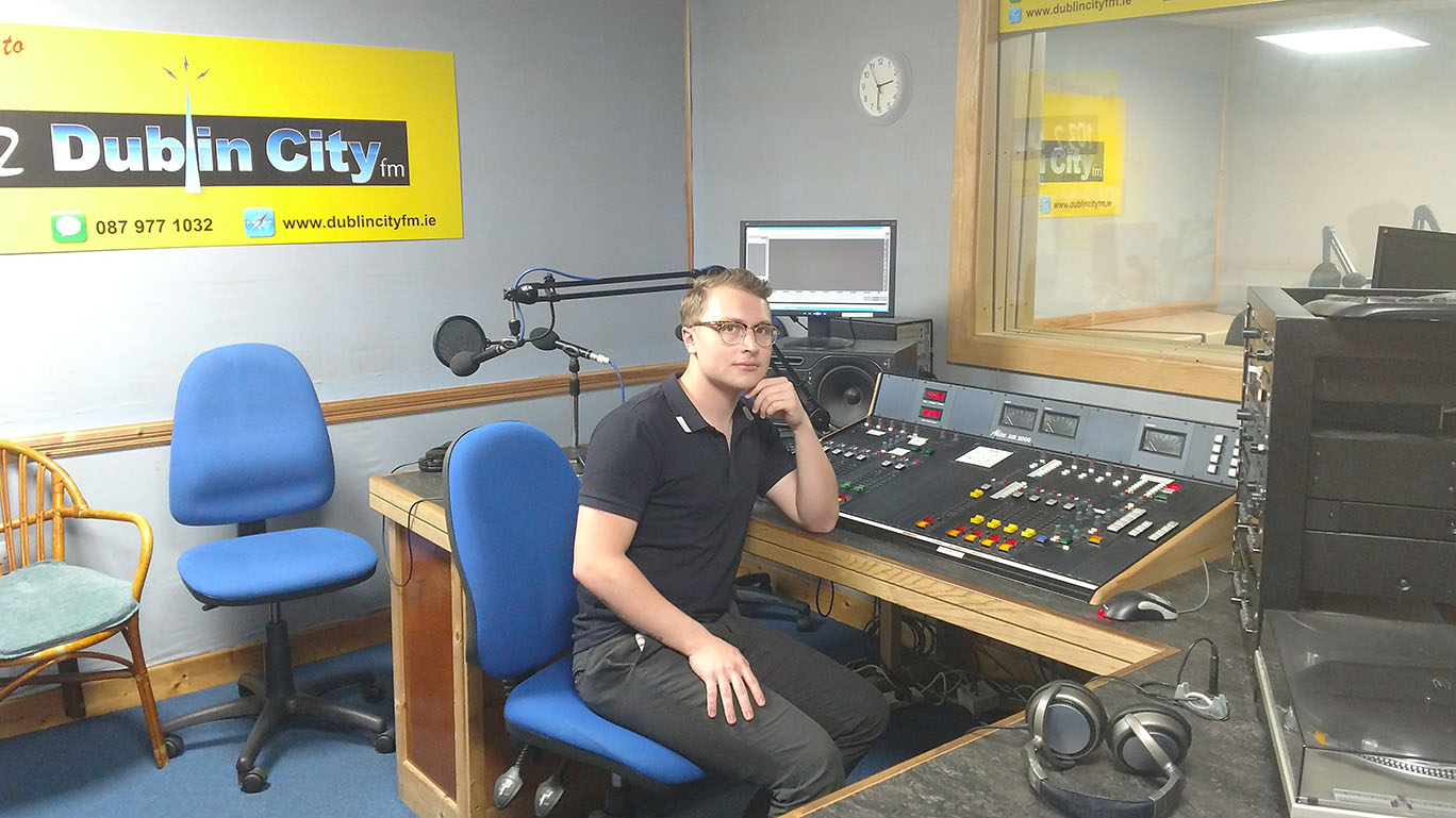 male student sits in radio studio