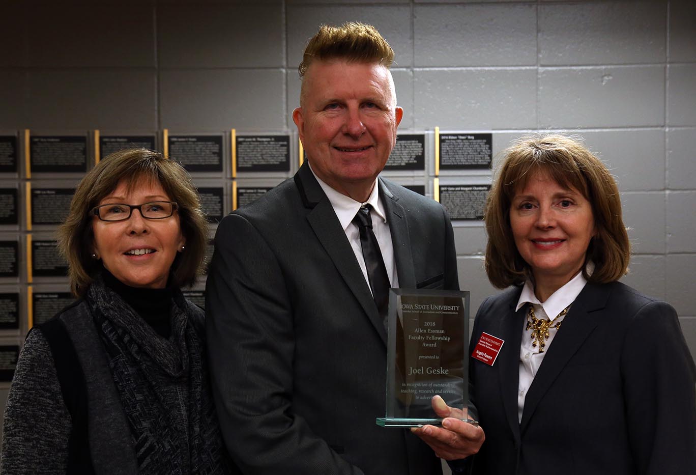 Denise Essman, Joel Geske and Angela Powers stand with plaque