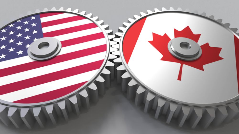 Two gears interacting, one with American flag and one with Canadian flag on the face of them.