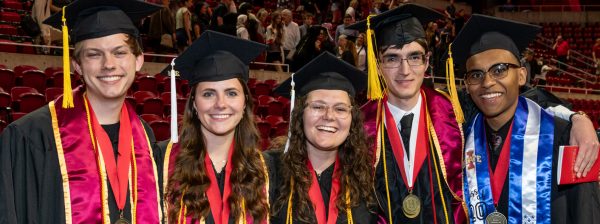 Five students wearing regalia standing shoulder to shoulder smiling at the camera at an LAS Convocation ceremony