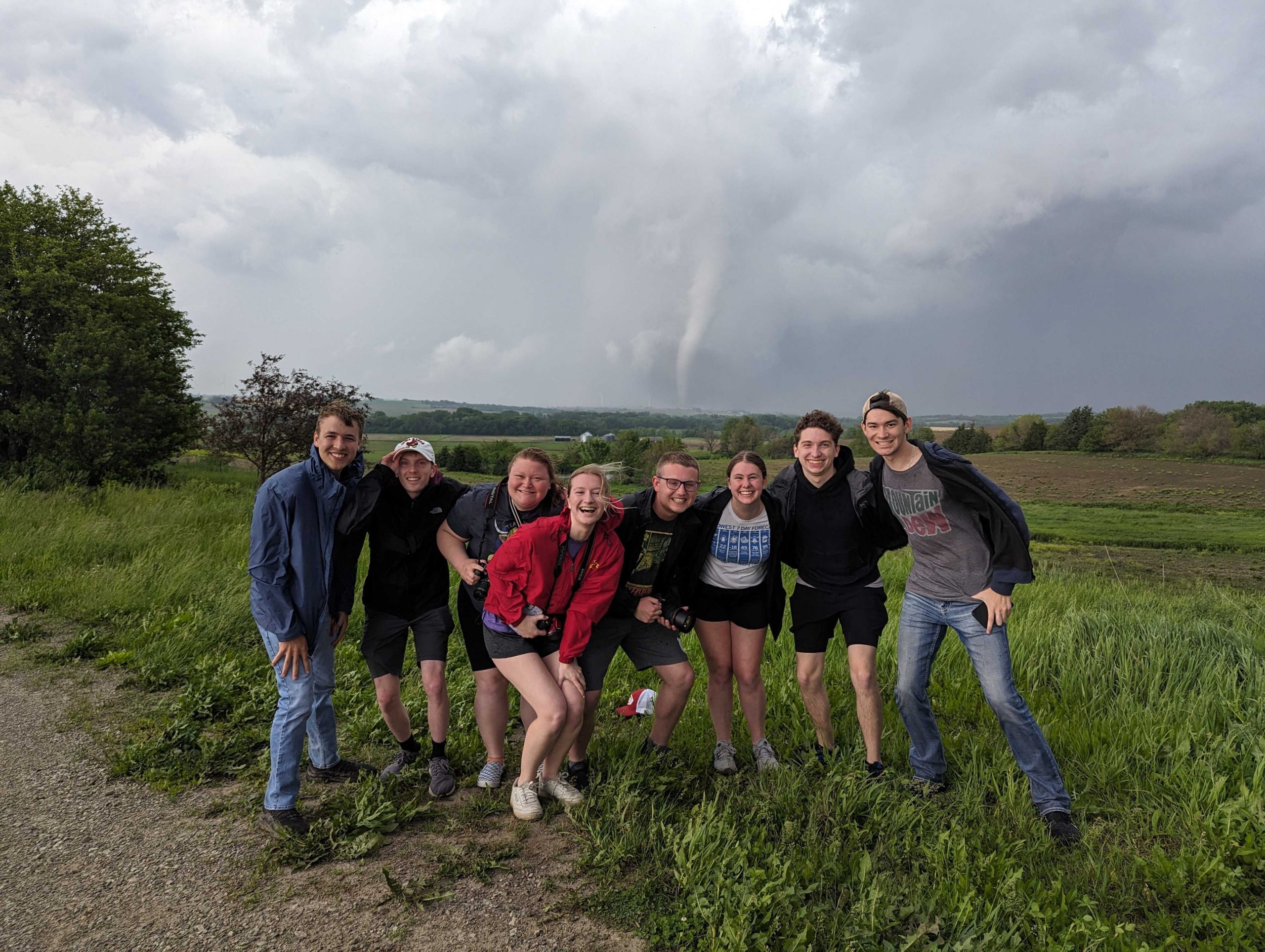 Students storm chasing with a tornado in the distant background