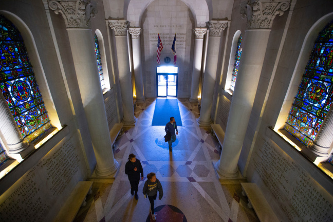 Three people walking through the Gold Star Hall from an aerial angle.