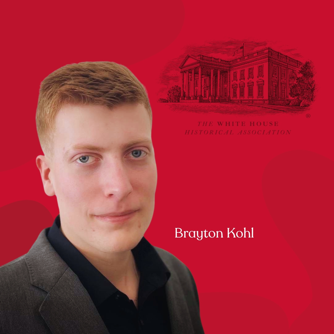 A professional headshot of a young man with short red hair and blue eyes, wearing a dark suit jacket over a black collared shirt. He has a confident yet neutral expression. The background is deep red, featuring a detailed illustration of the White House with the text "The White House Historical Association." Below the illustration, the name "Brayton Kohl" is displayed in white text.