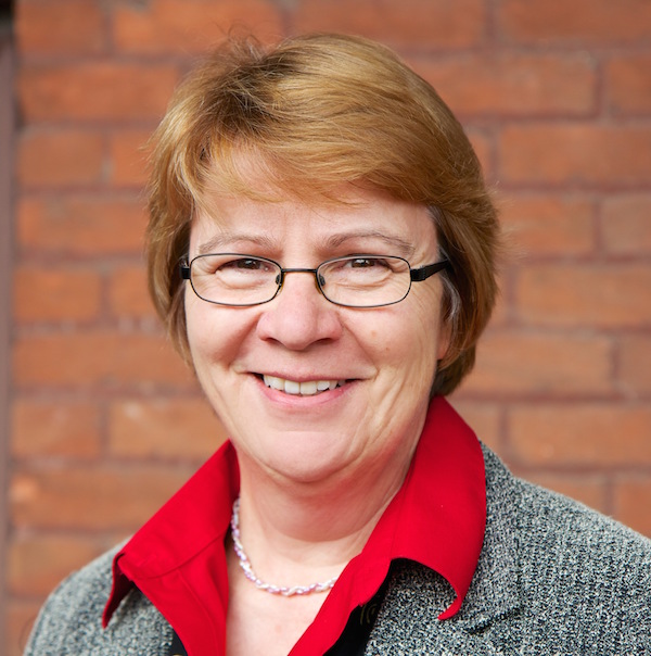 Dean Beate Schmittmann smiling in front of a brick wall.