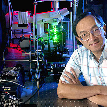 Edward Young beside a machine with a laser and a microscope.