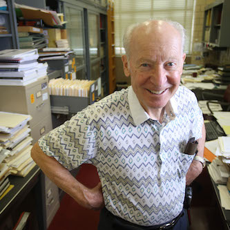 Karl Gschneidner in his office surrounded by papers.