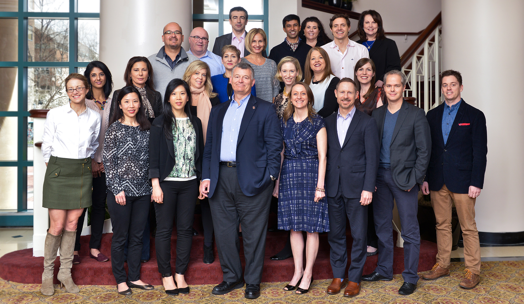 A group shot of Estee Lauder employees posed on a staircase at a symposium.