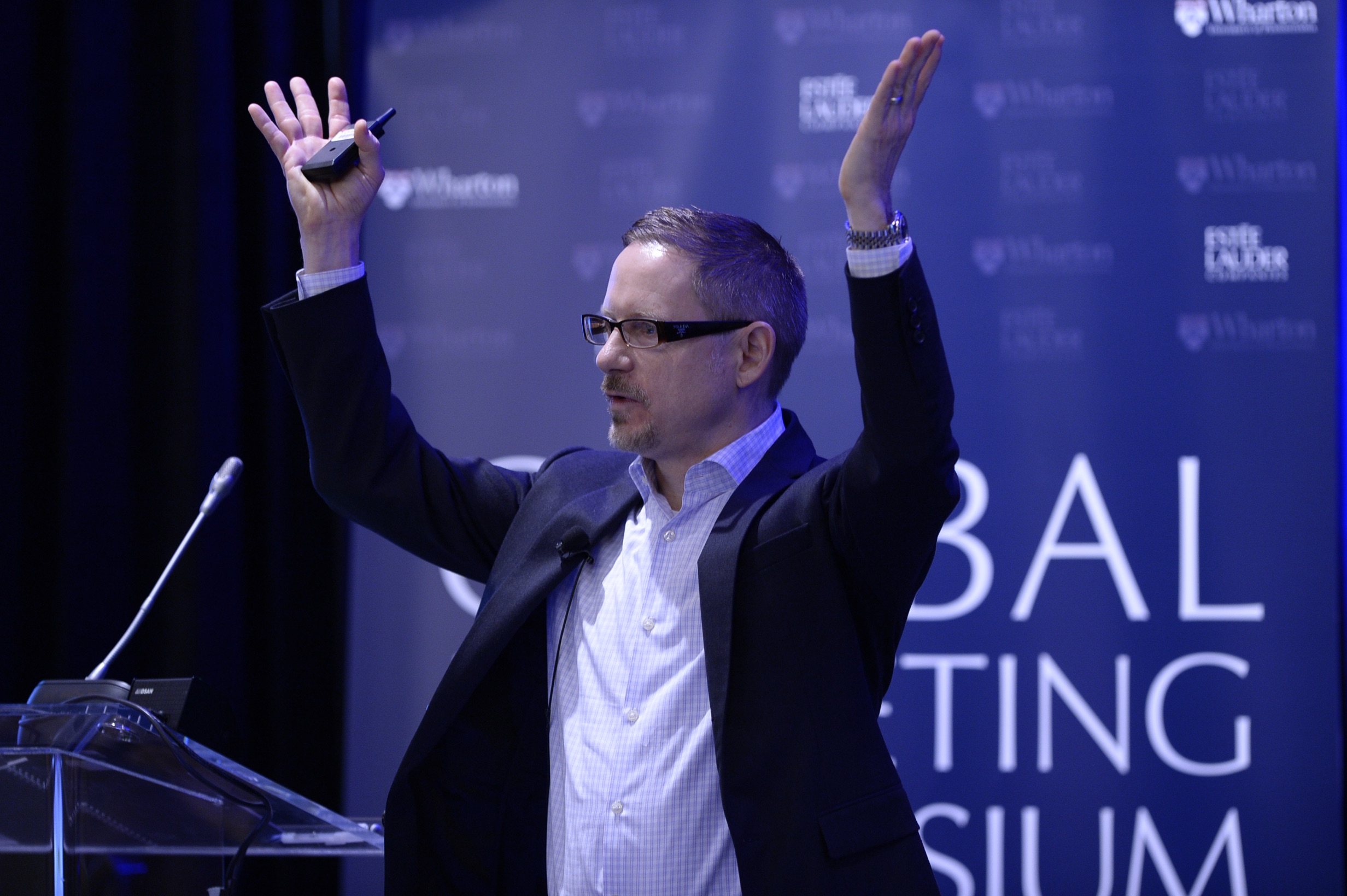 Doug Jensen stands in front of an Estee Lauder backdrop giving a presentation.