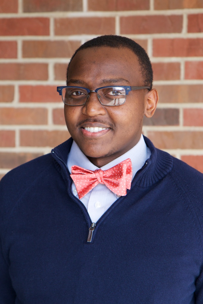 Portrait style photo of KB Gwebu in front of a brick wall.