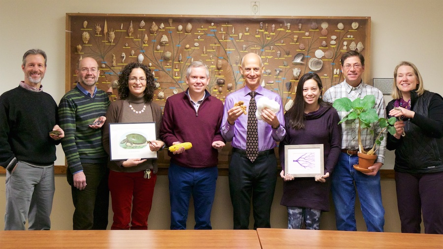 A group of faculty hold representations of the plant species they each research.