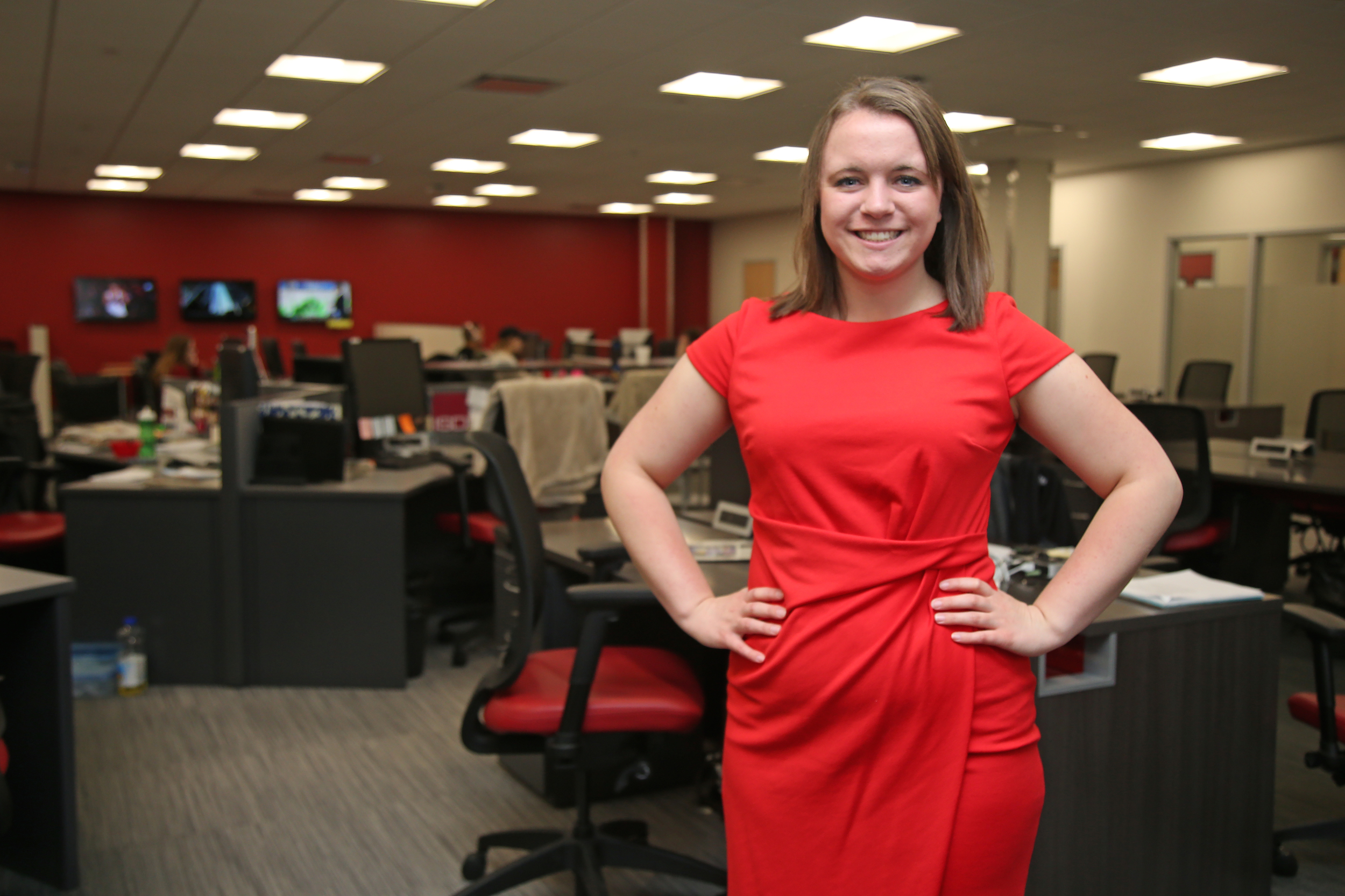 A portrait style photo of Emily Barske with the ISU Daily newsroom in the background.