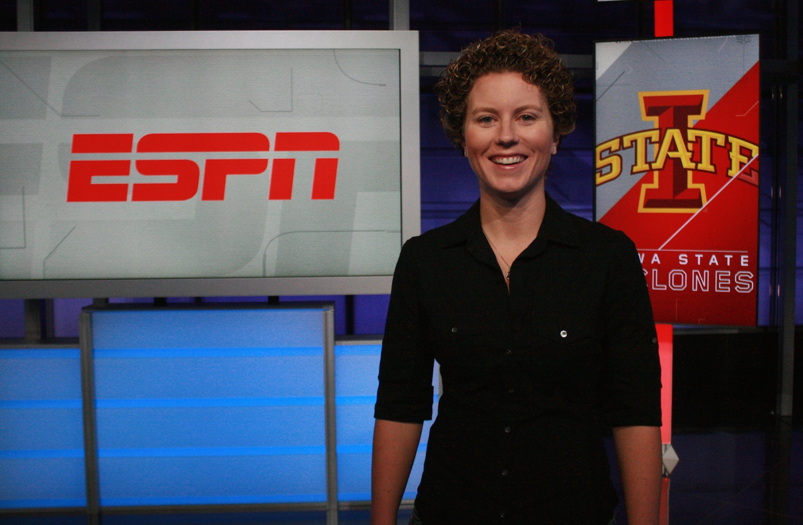 Emma Reed on set at ESPN with digital signs displaying the ESPN logo and Iowa State logo behind her.