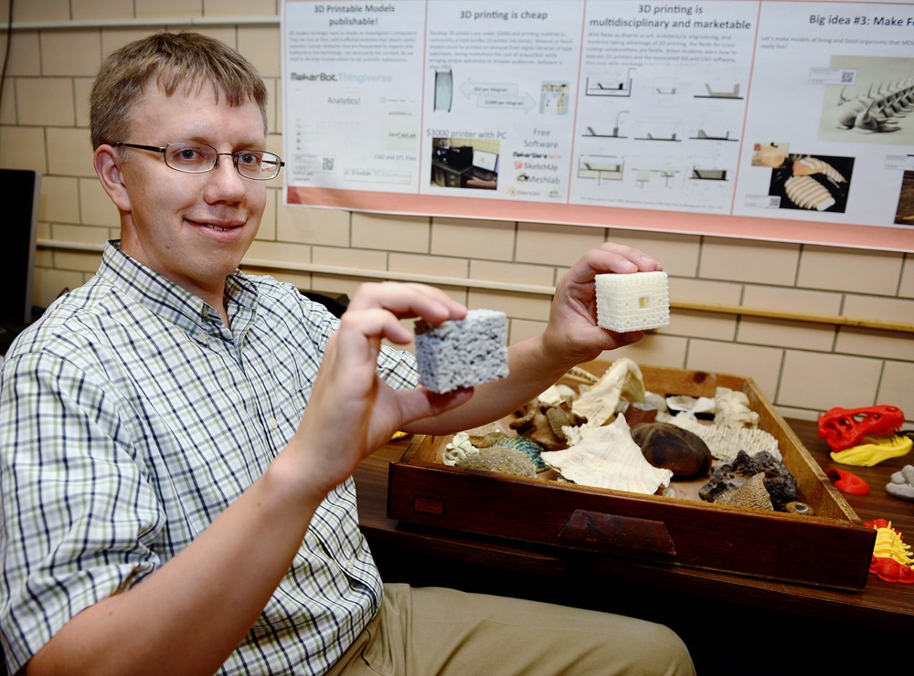 Frank Hasiuk holds up a 3-D printed reservoir rock and a model of rock porosity in his office.