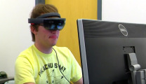 Photo of student wearing a HoloLens while viewing a computer screen.