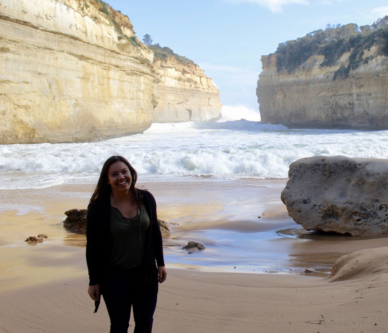 Student stands on the beach at Loch Ard Gorge in Australia.