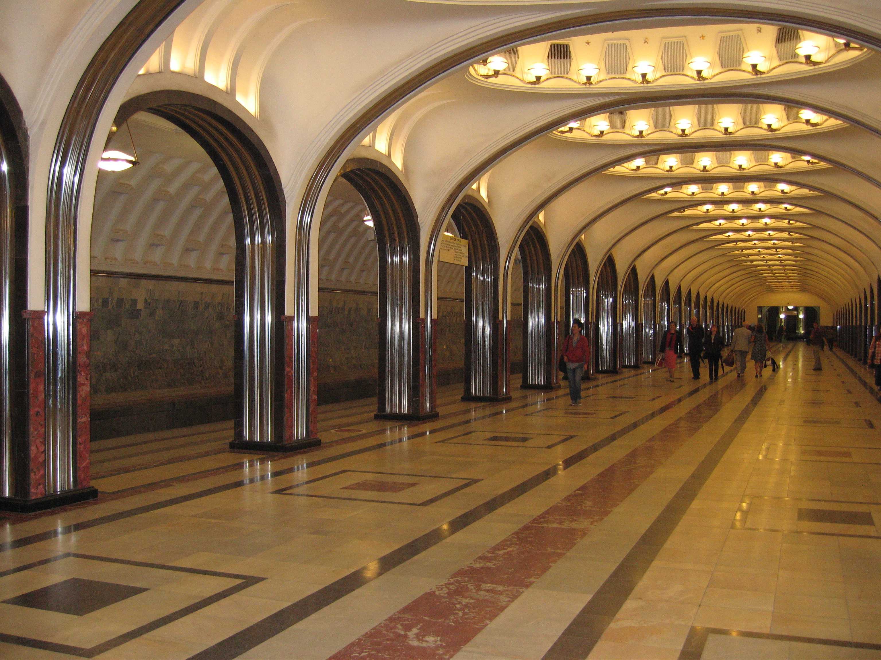 Several travelers walk through a mostly empty Mayakovsky Station.