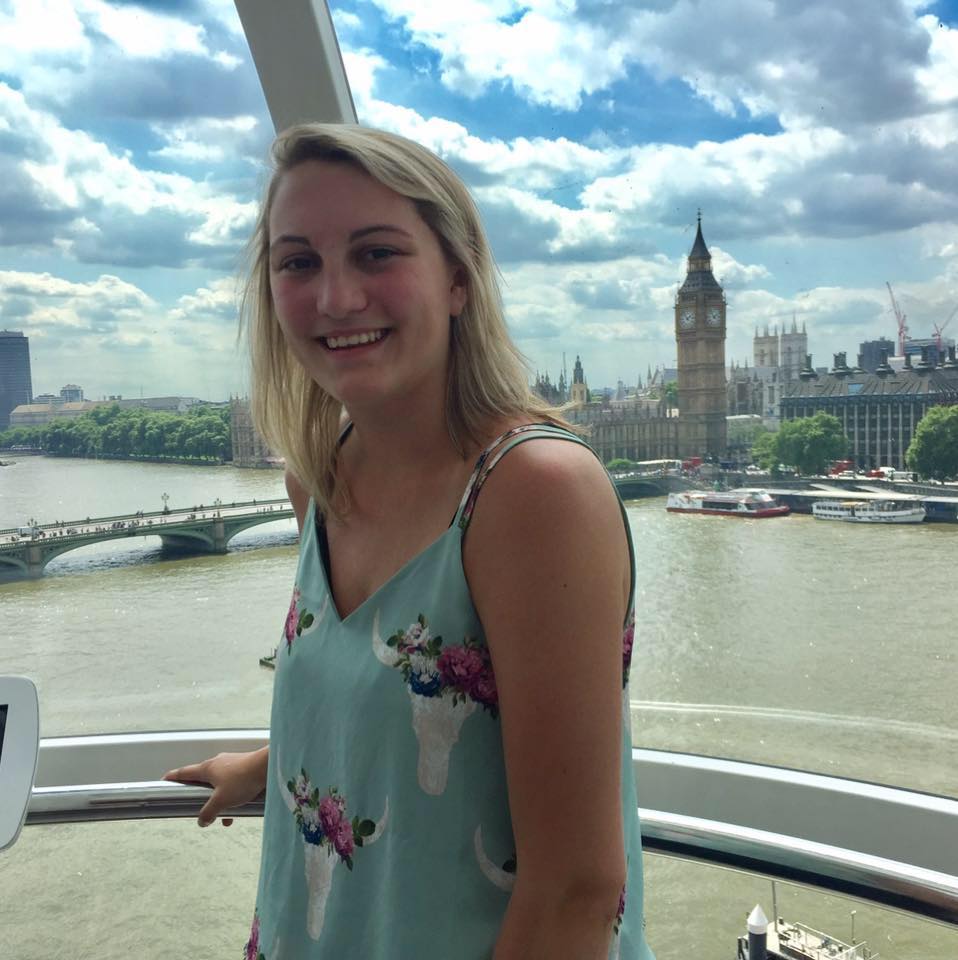 A student poses on the London Eye with Big Ben in the distance.