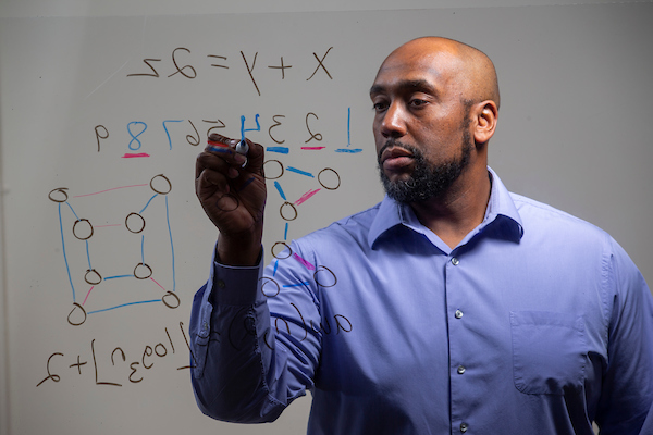 Professor writes formulas on glass board