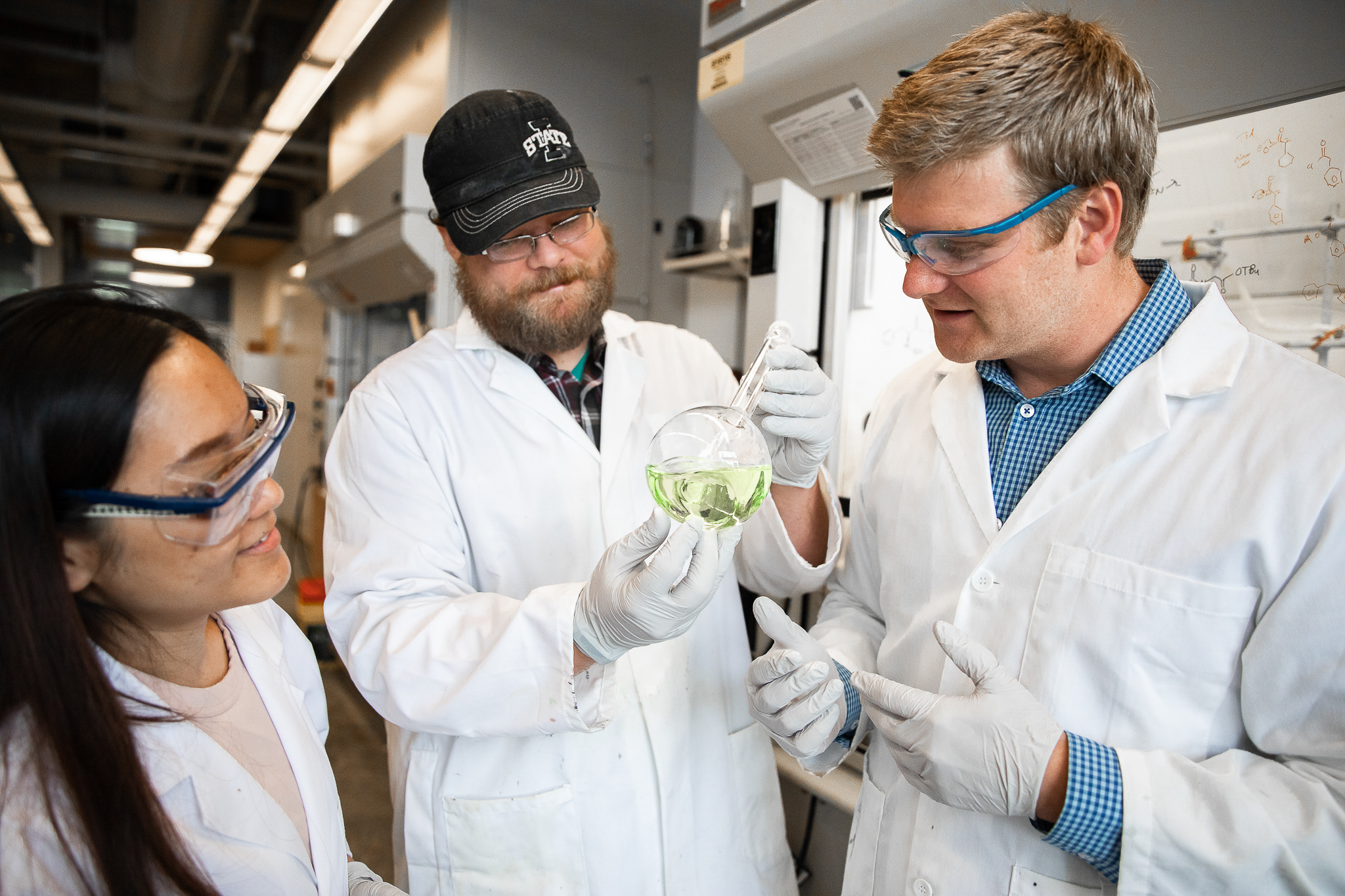 Dr. VanVeller and two students examine a flask