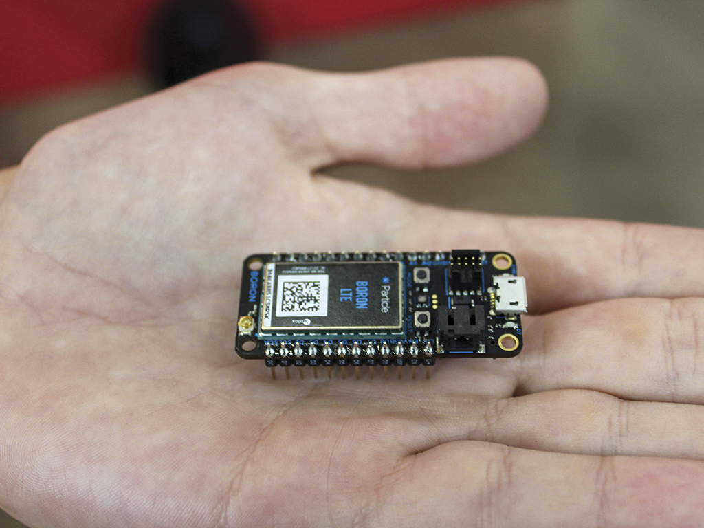 A microcontroller device, held in the palm of Dillon Jensen