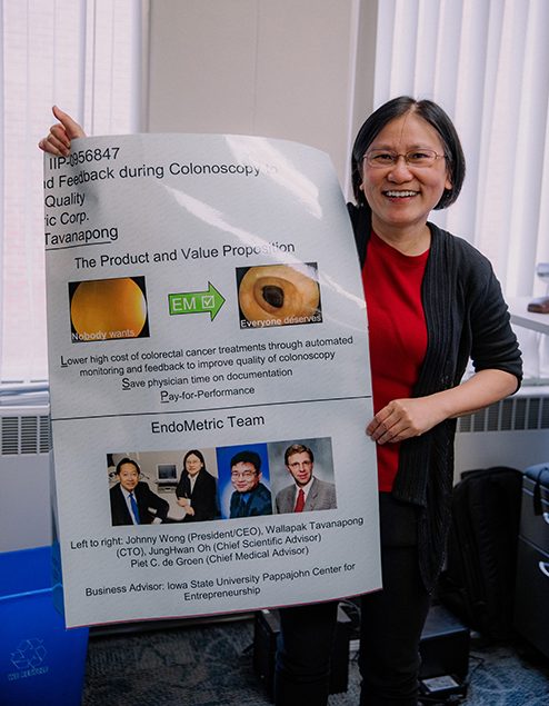 Professor Wallapak Tavanapong poses with a poster which showcases colonoscopy images from the software she developed