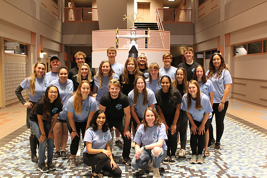 23 students who helped to plan the Stupka Symposium pose in the Molecular Biology Building atrium