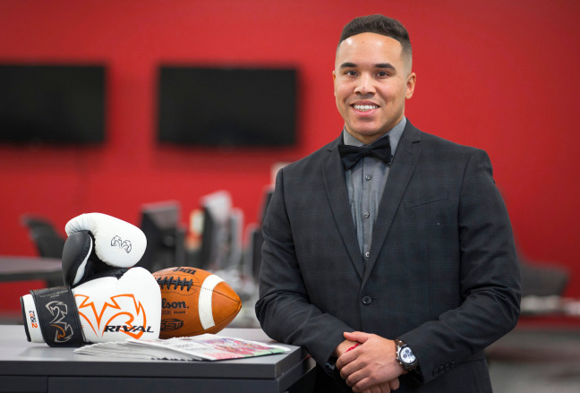 Nik Heftman stands at a desk with sports equipment on it.