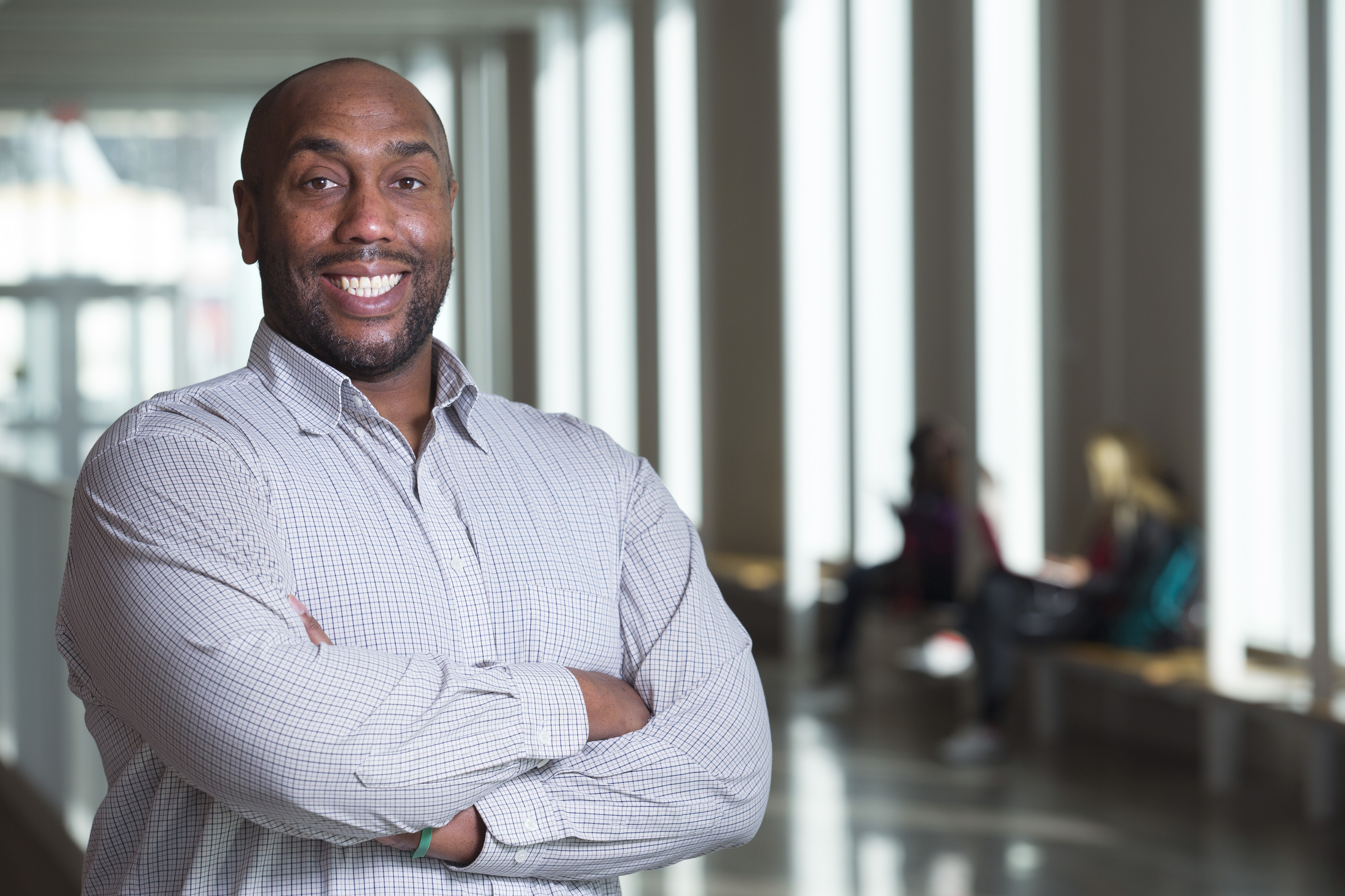 Michael Young standing in a hallway with students studying in the background.