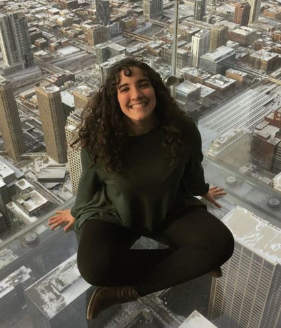 A student sitting on a glass floor with city skyscrapers in the background.