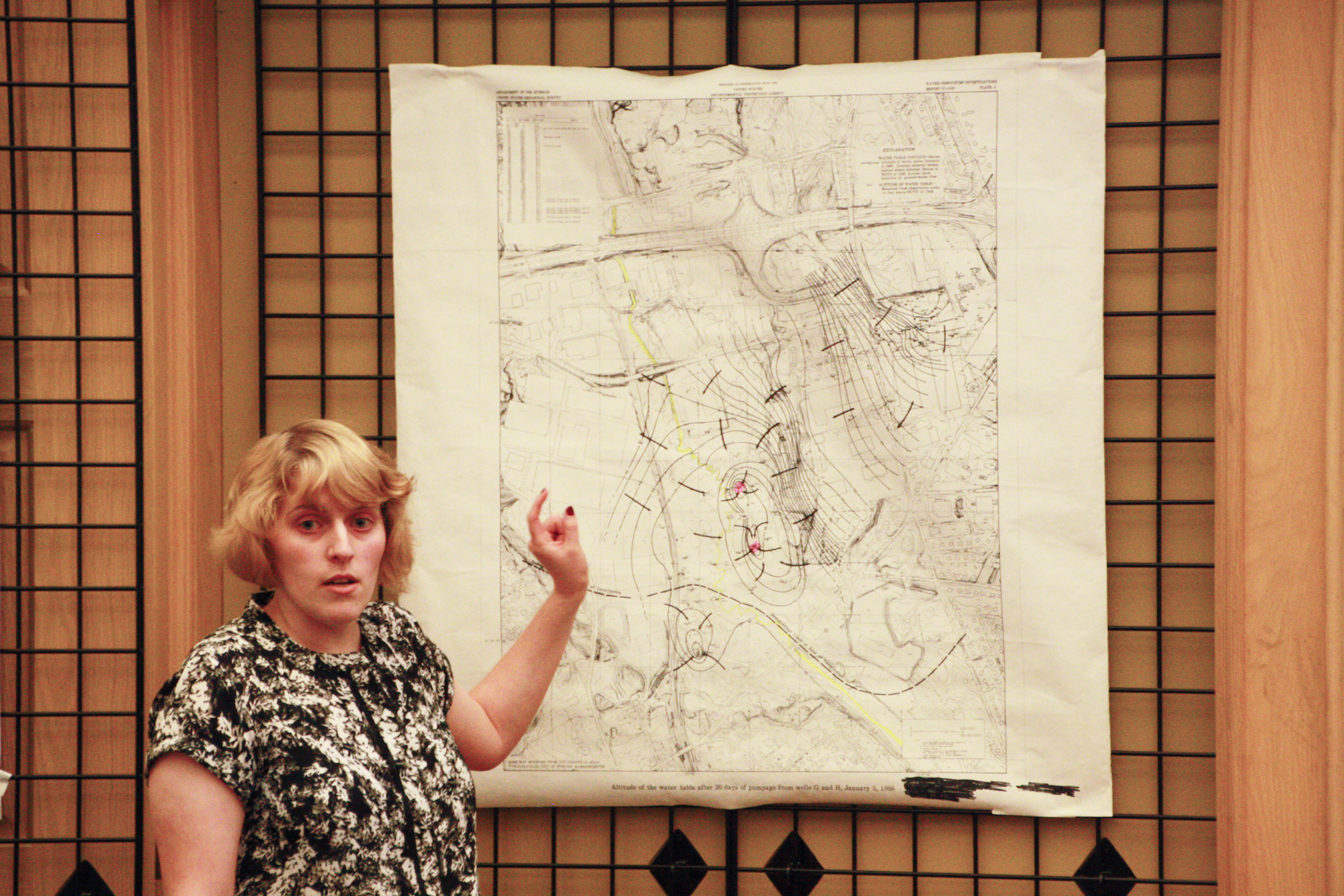 A woman stands in front of a map and points.