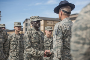 Airmen stand at attention. A leader shakes Gour Maker's hand.