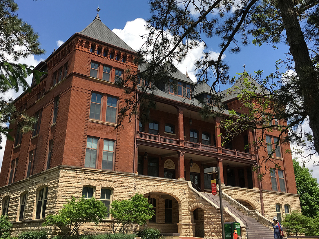 Catt Hall with blue skies and spring leaves.