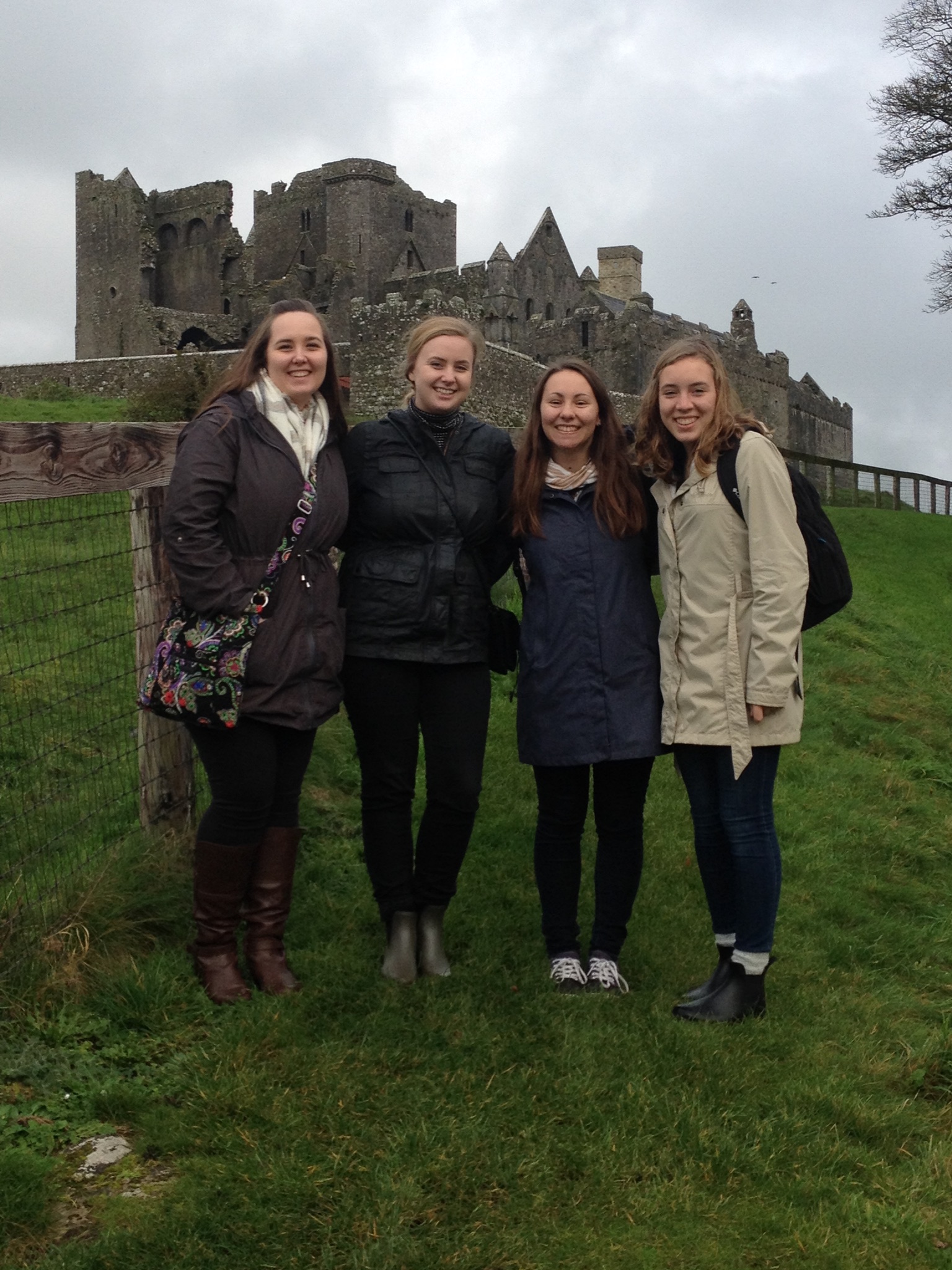 Four students stand in front of a historic site in Ireland.