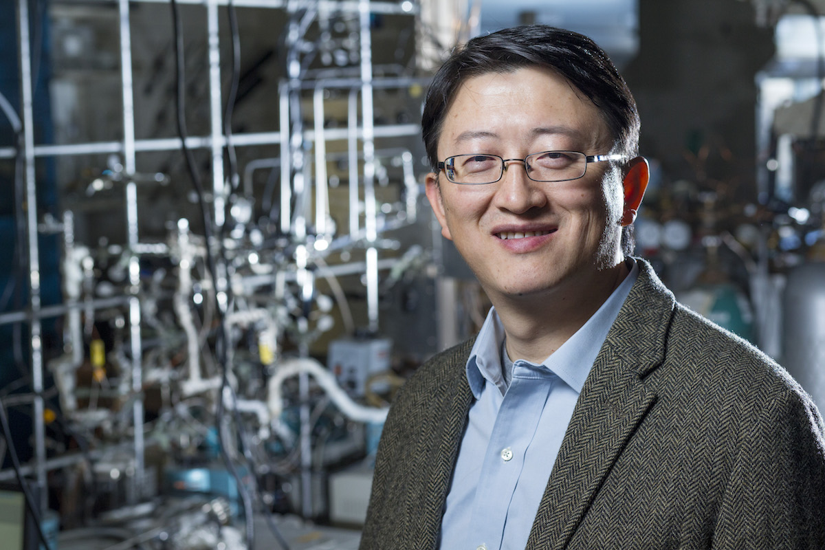 Wenyu stands in a lab with chemistry equipment behind him.