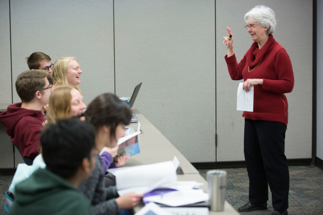 A lecturer talks to a group of students.