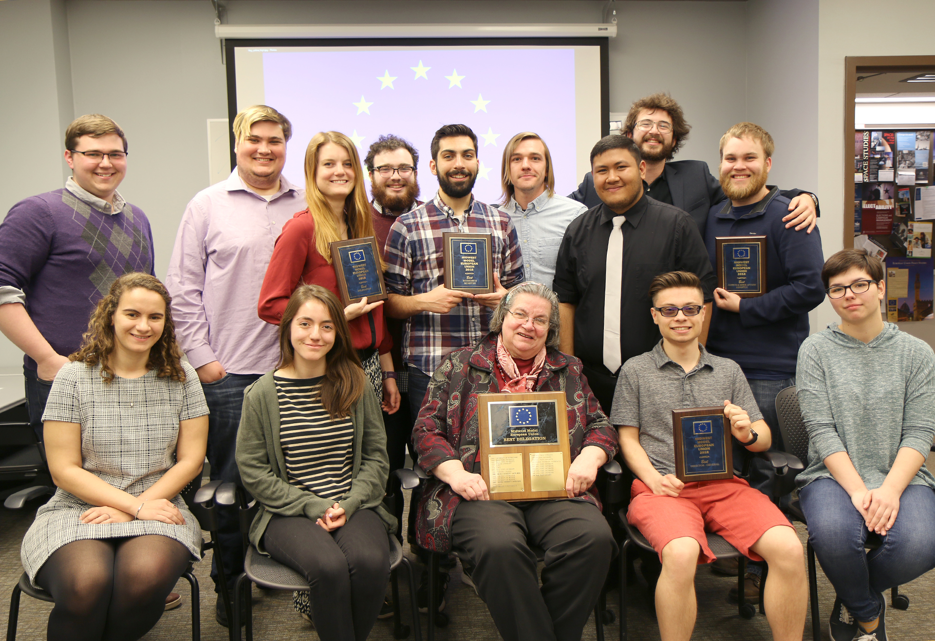 A group of students pose, several with plaques.