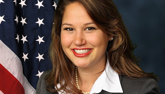 Melanie Thwing in front of a flag.