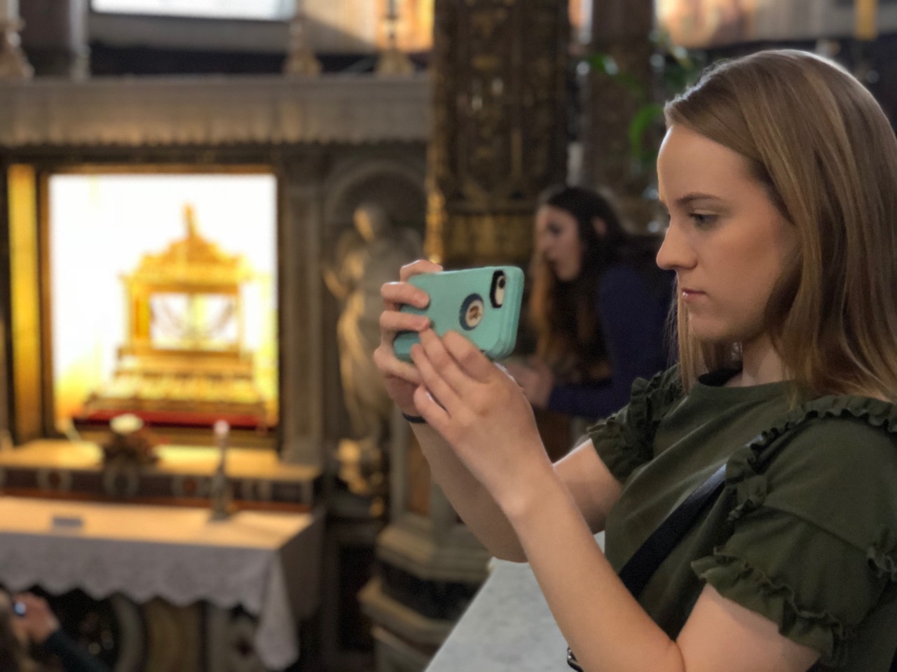 A student takes a picture with a phone inside of a museum.