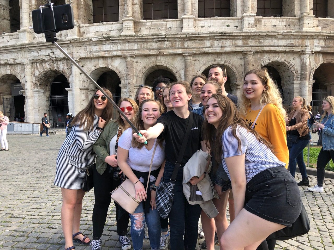 The group takes a selfie in front of the Coliseum in Rome.