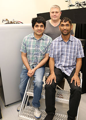 Three guys sitting in front of lab equipment.