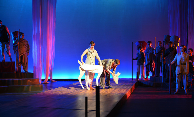 Students stand on stage with a puppet deer.