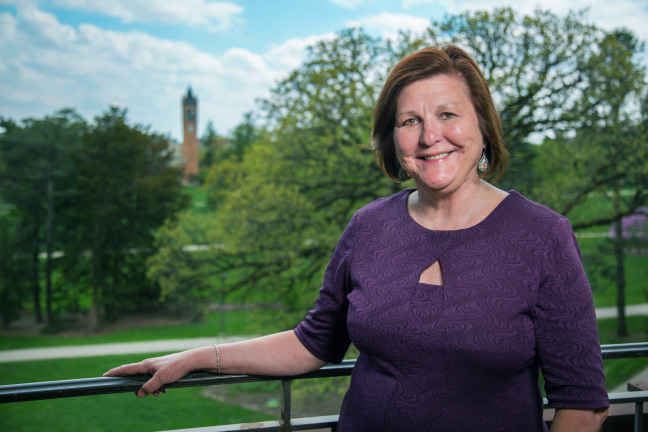 Dianne Bystrom stands on a balcony overlooking campus.